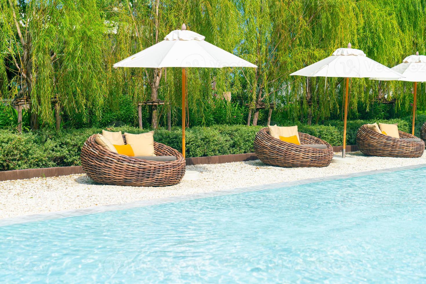 outdoor patio chair with pillow and umbrella around swimming pool photo