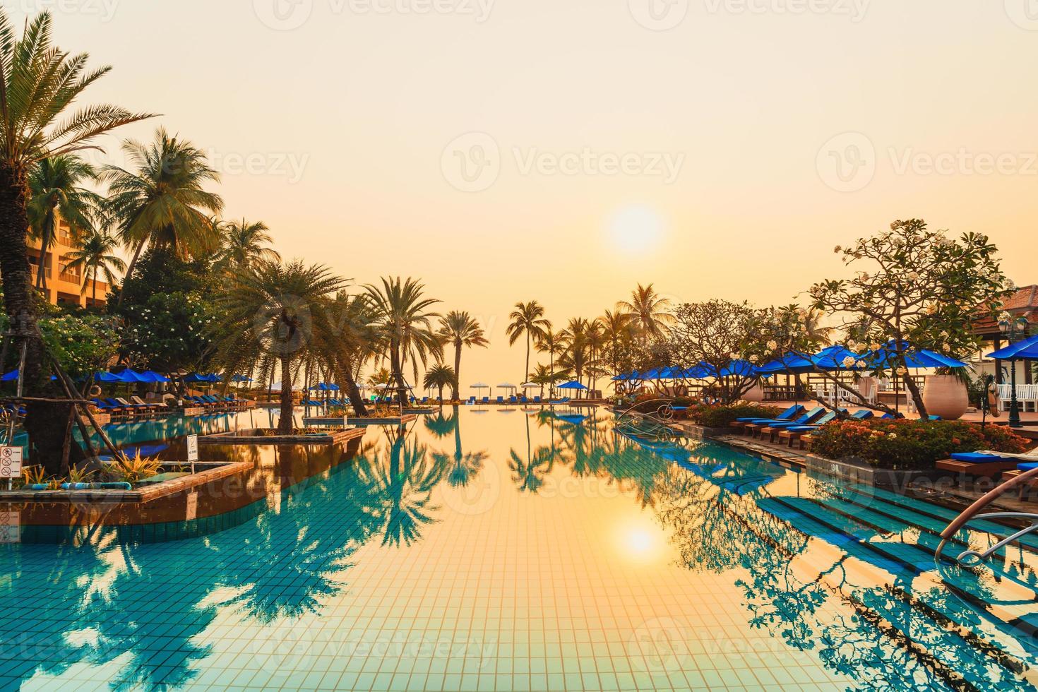 Palmera con sombrilla piscina en hotel resort de lujo al amanecer. foto