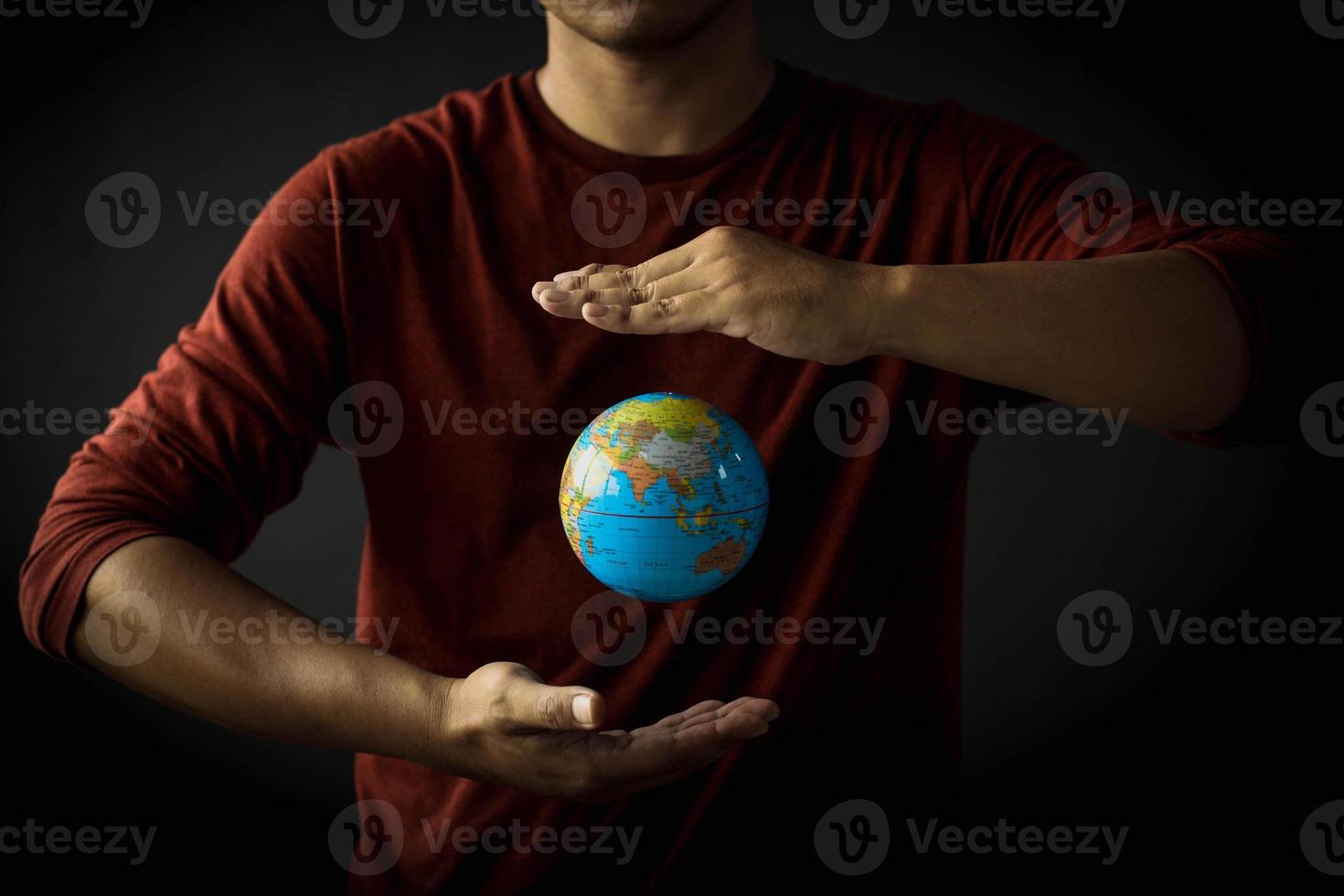 Hand of a man protecting a globe floating between his hand on black background. Earth day concept with low key tone photo