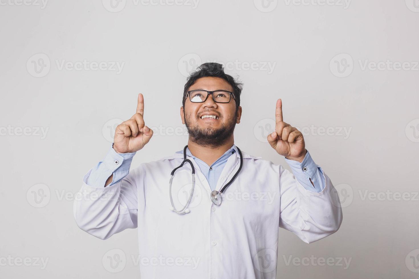 Cheerful male doctor pointing with both hands up isolated on white background photo