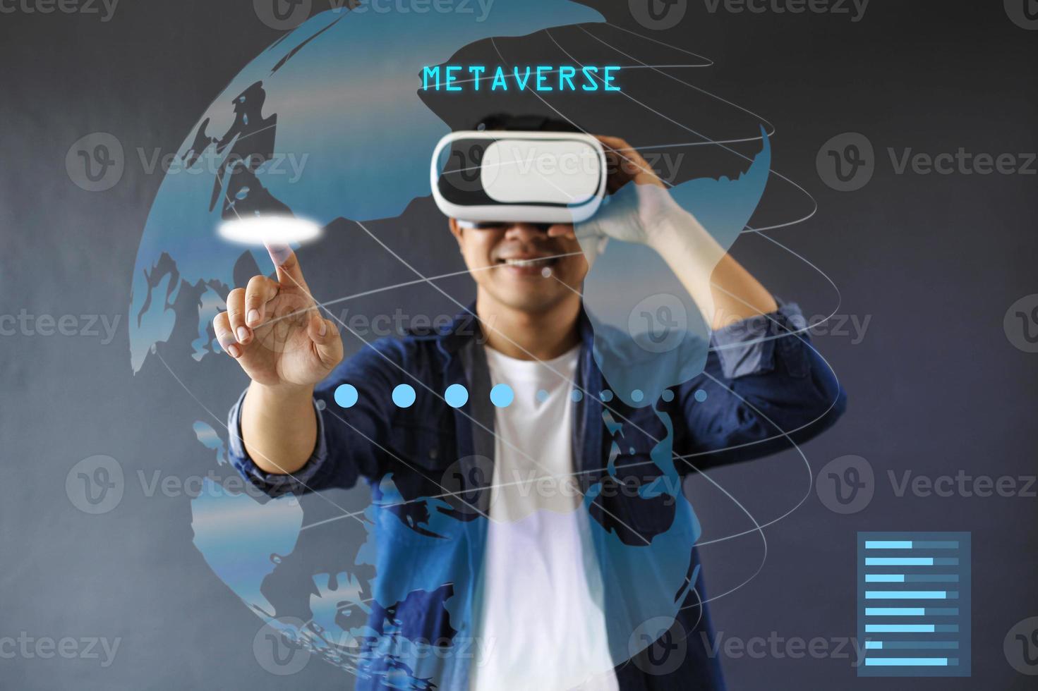 Smiling man is use VR googles and touch hologram screen againts dark grey background. photo
