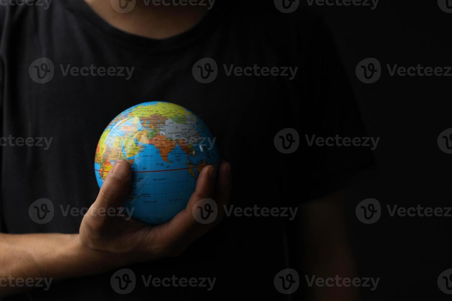 Hand holding globe on black background with copy space. Earth day concept with low key tone photo