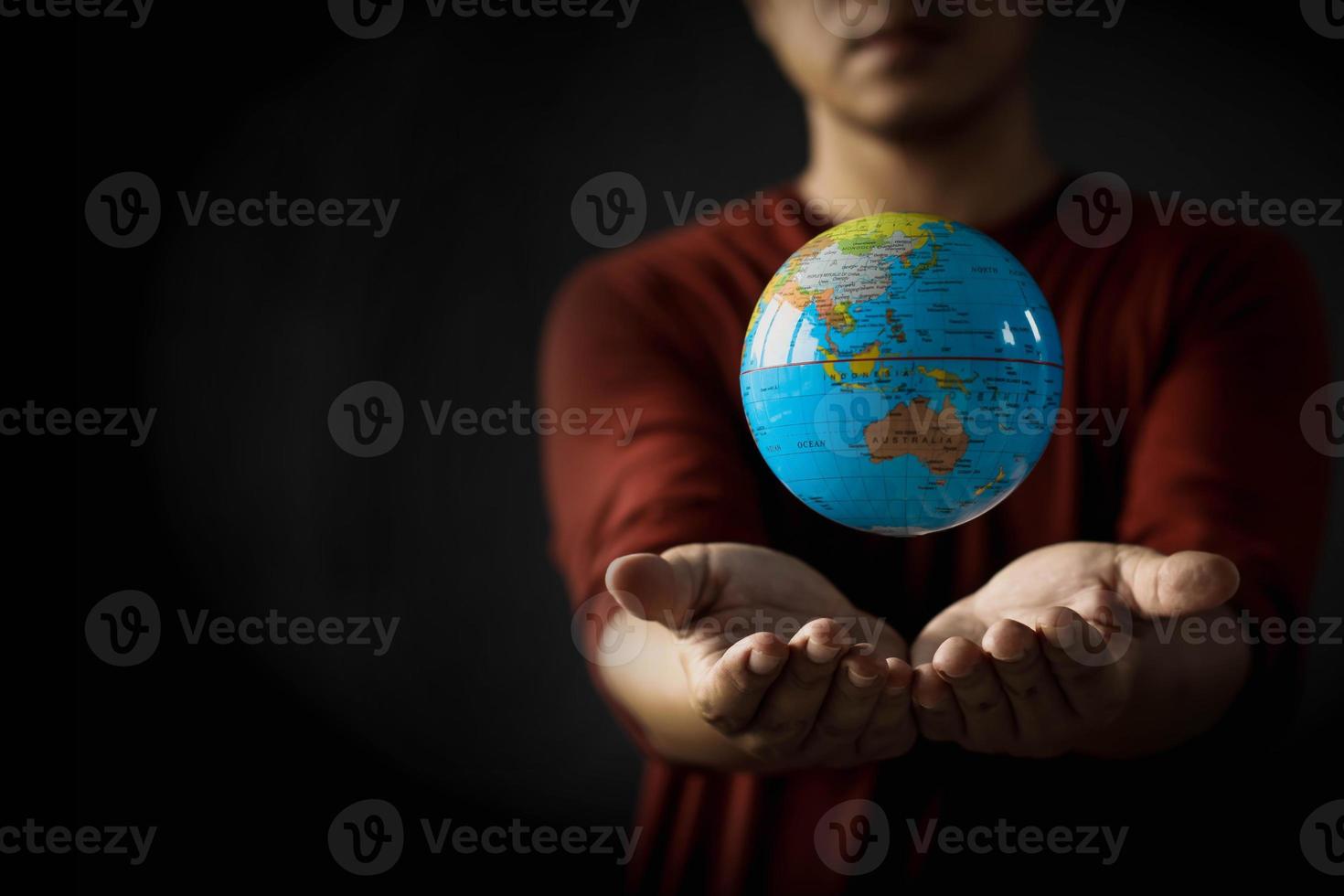 Close-up of a globe floating above a man's hand on a blurred background. Earth day concept with low key tone photo