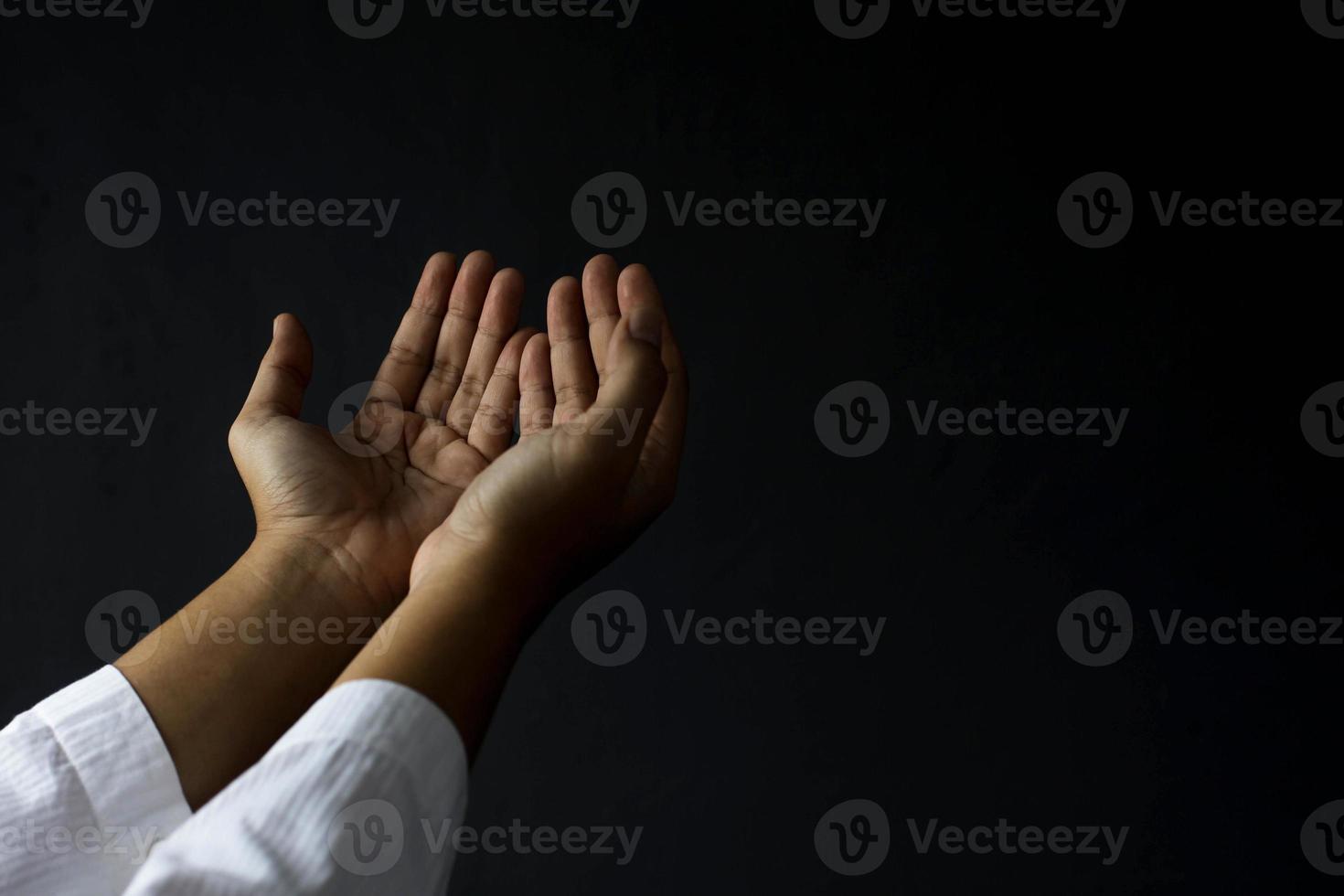manos musulmanas rezando aisladas en fondo negro con espacio para copiar. concepto de ramadán kareem foto