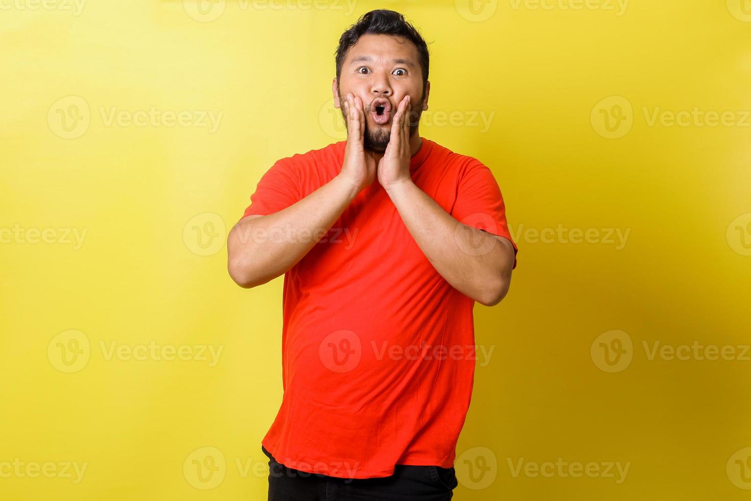 Fat asian guy shouting at camera isolated on yellow background photo