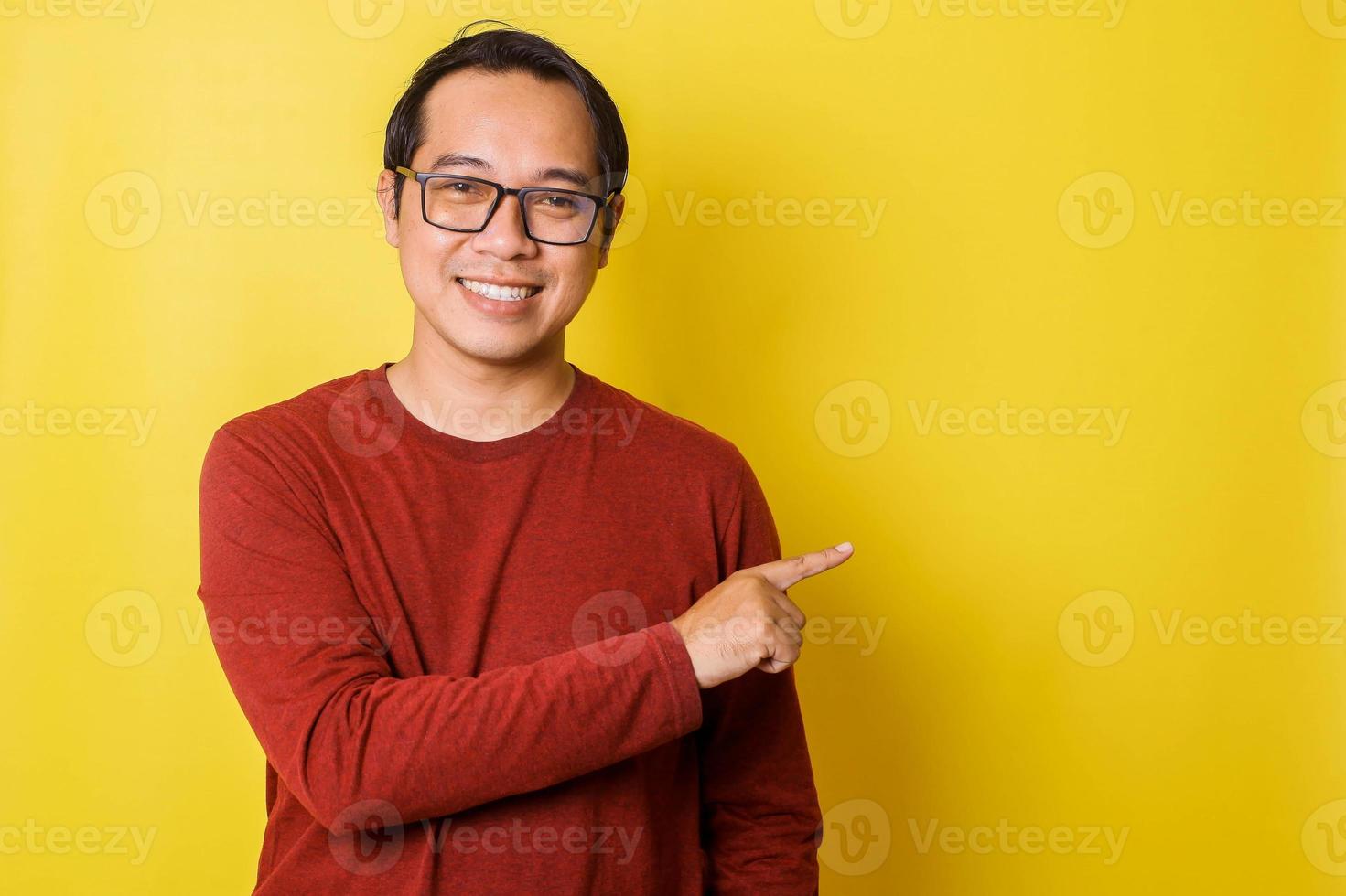 Casual man in glasses pointing sideways with one hand isolated on yellow background photo