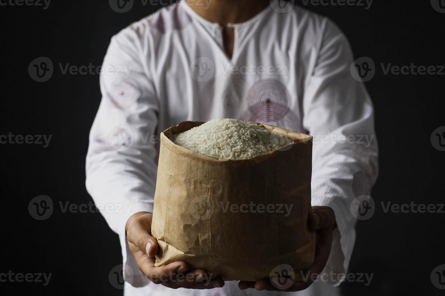 Muslim hand holding alms bag of rice isolated on black background photo
