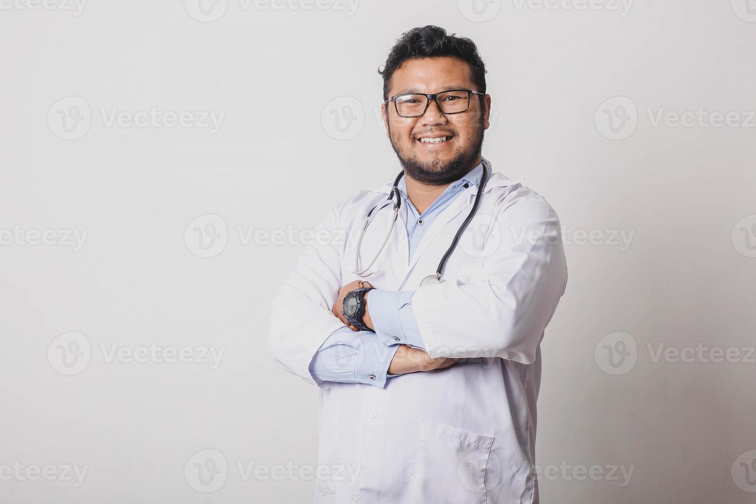 Thoughtful male doctor standing and crossing his arms in hospital photo