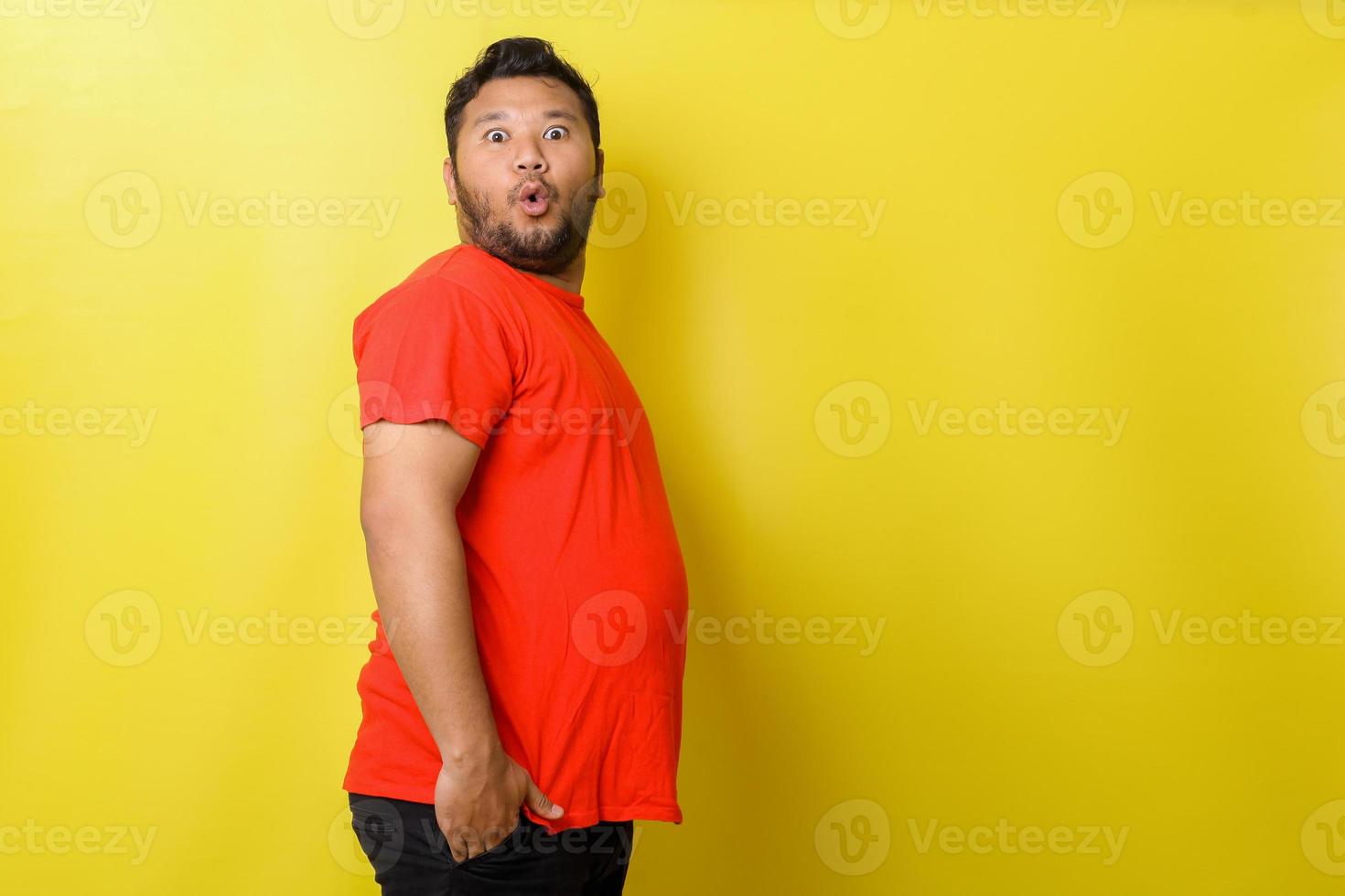Fat asian guy with surprised expression isolated on yellow background photo