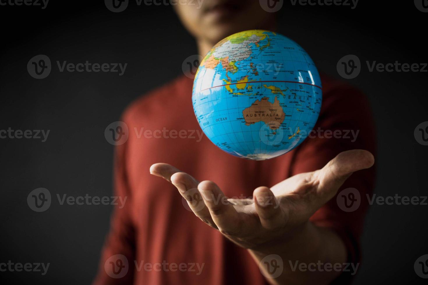Close-up of a globe floating above a man's hand on a blurred background. Earth day concept with low key tone photo