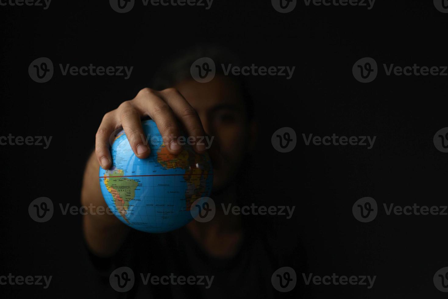 Hand holding globe on black background with copy space. Earth day concept with low key tone photo