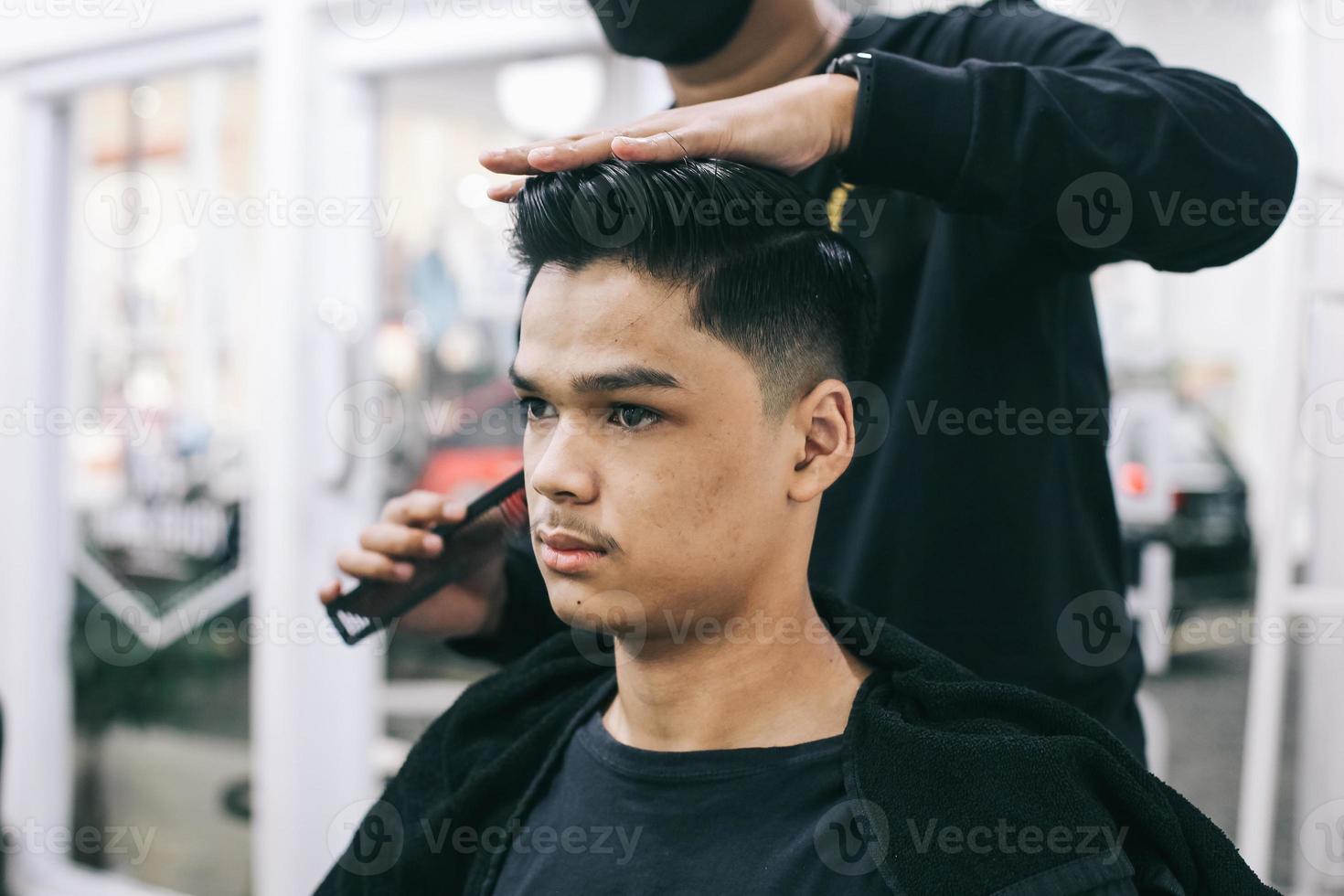 Asian man at barbershop. Hair stylists fix consumer's hair. Self-care, masculine beauty. Barber. photo