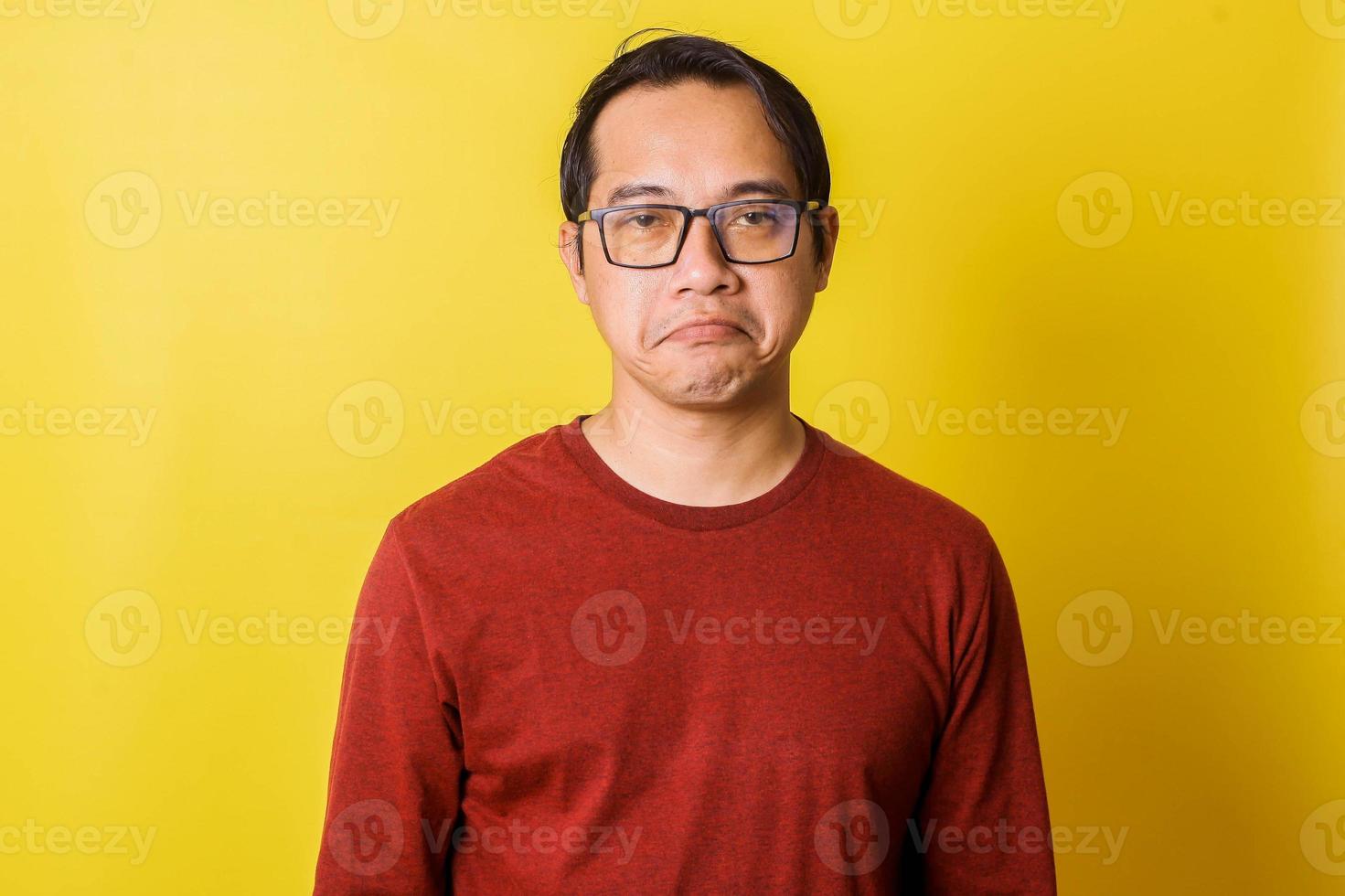 Casual man in glasses with disappointed facial expression isolated on yellow background photo