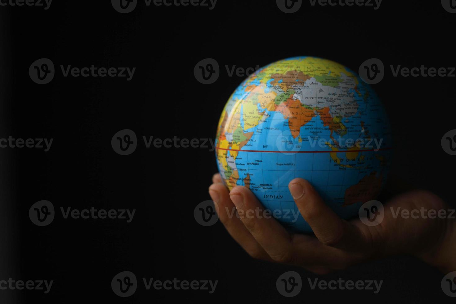 mano sosteniendo globo sobre fondo negro con espacio de copia. concepto del día de la tierra con foto de tono bajo