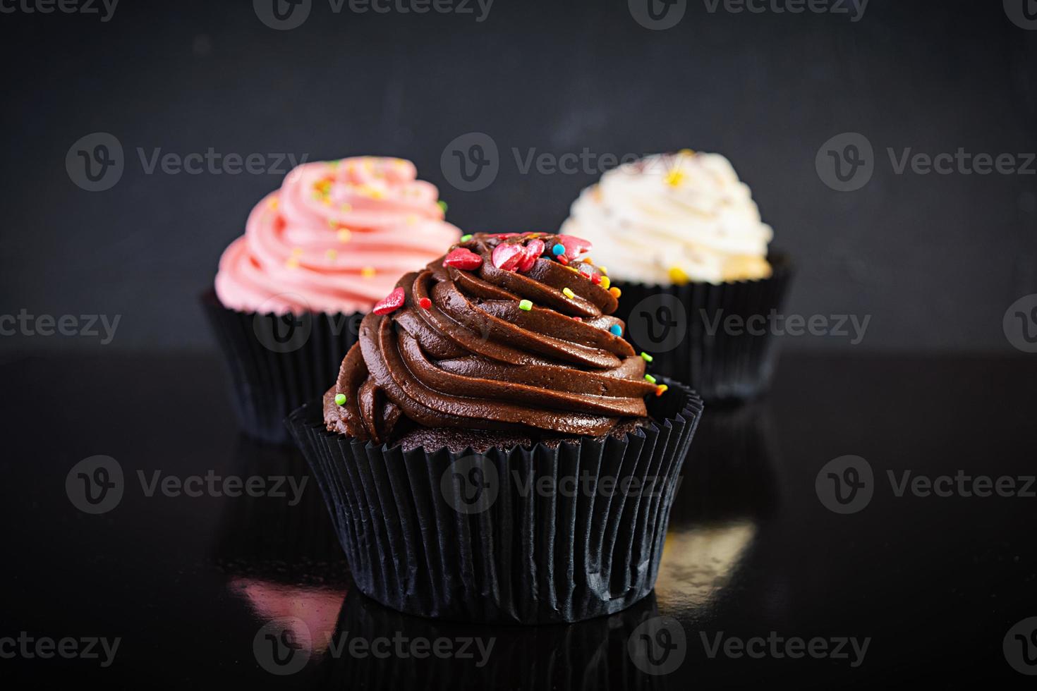 sabrosos cupcakes coloridos aislados sobre fondo oscuro. deliciosa magdalena foto