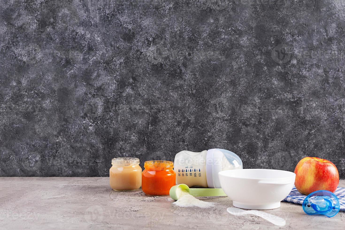 Bowl with vegetables puree and bottle of baby food on gray background photo