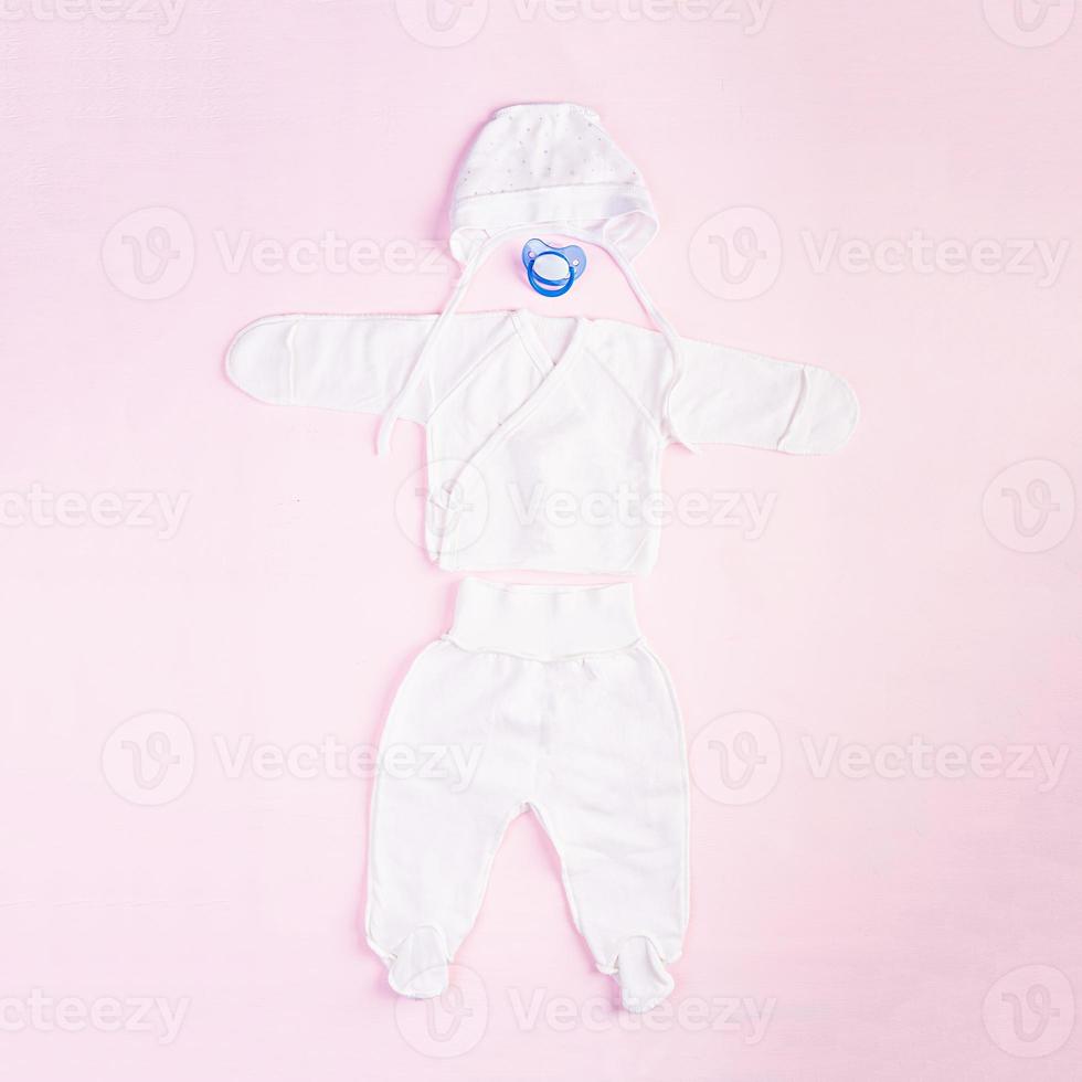 Baby clothes and other stuff for child on pink background. Newborn baby concept. Top view photo