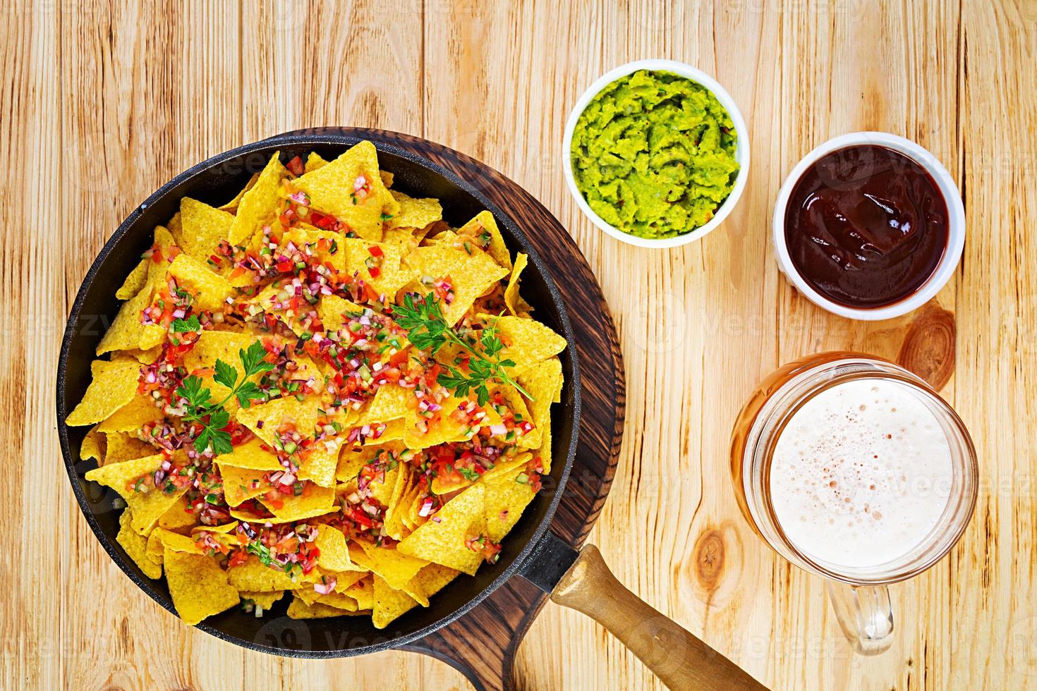 Mexican nachos with cheese. Corn chips with guacamole, salsa and tomato ketchup. photo