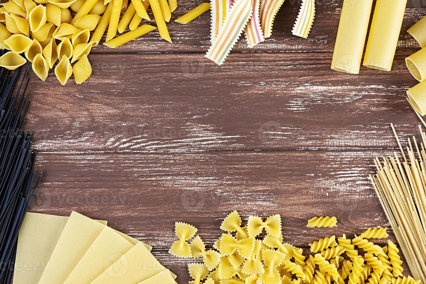 Different dry pasta on a wooden background. Top view photo