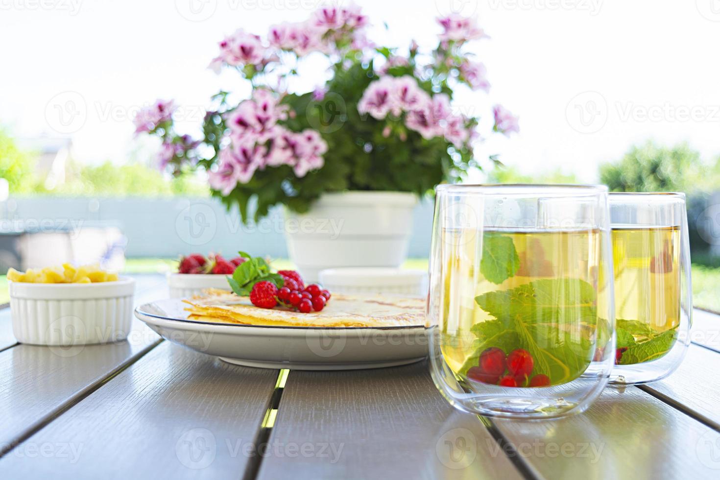 Pancakes with caramelized apples, raspberries, strawberries and red currants. Brunch with green tea and crepes. photo