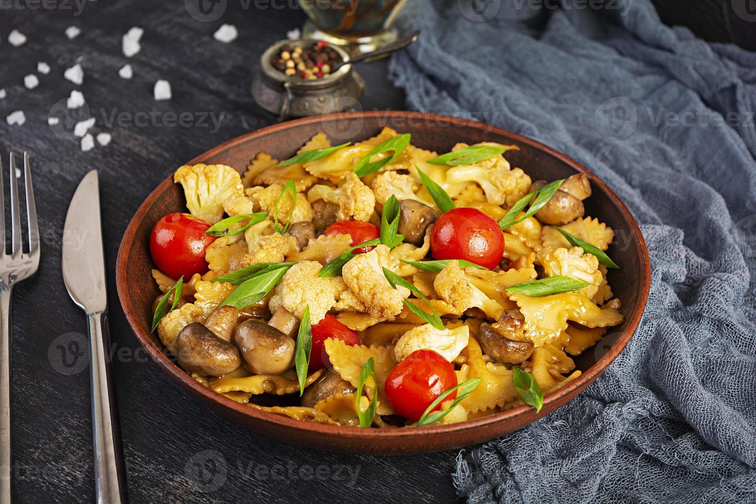 Stir fry farfalle pasta with vegetables, cauliflower and mushrooms photo