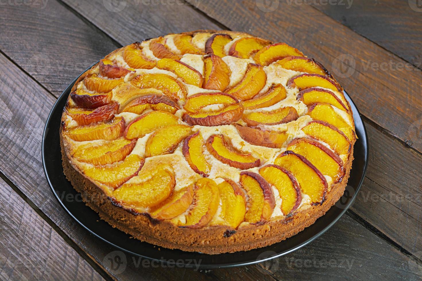 Delicious homemade peach pie on wooden background photo