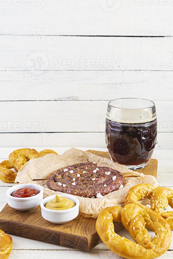 menú de comida para el oktoberfest. salchicha con salsa diferente, pretzel y vaso de cerveza oscura foto