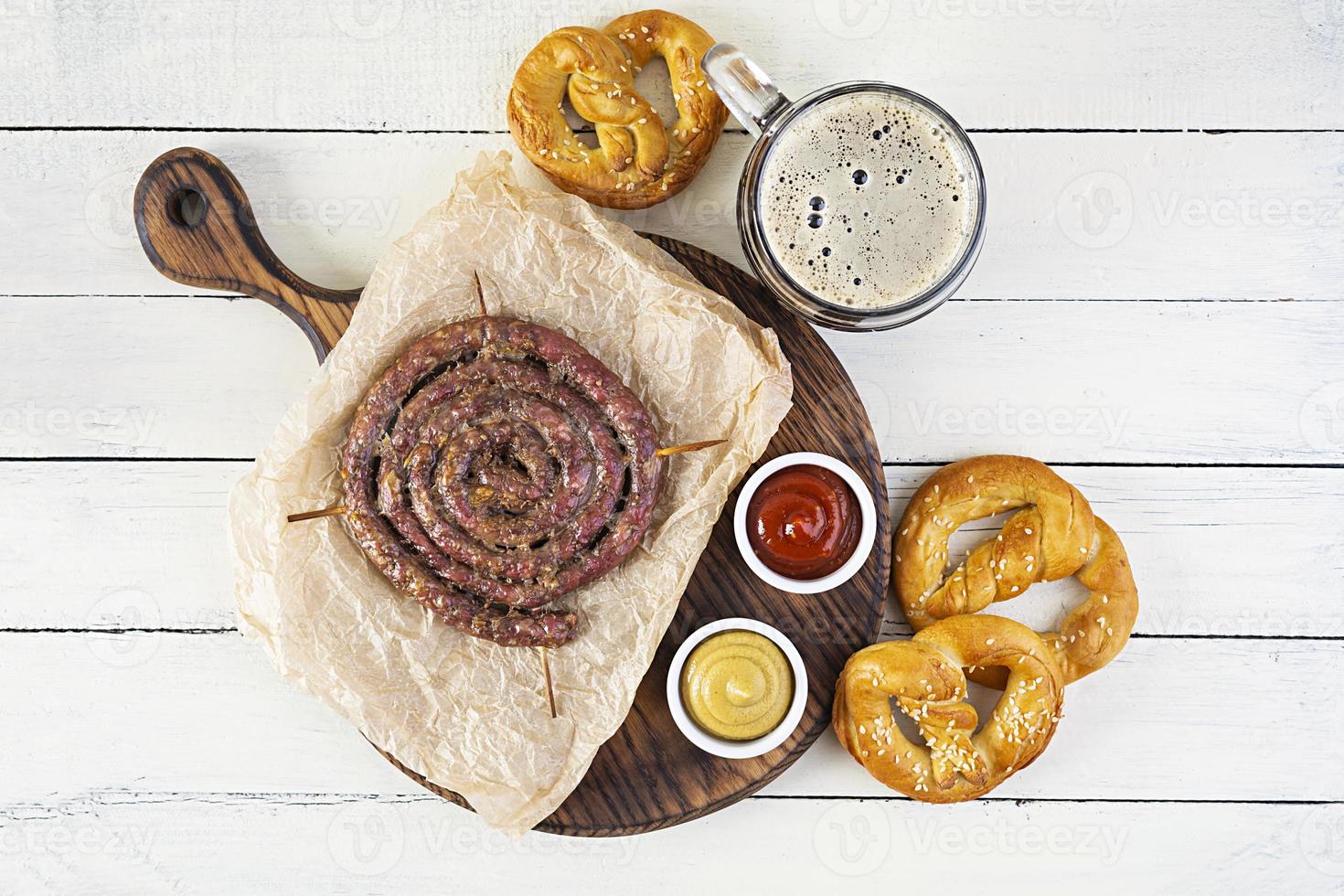 menú de comida para el oktoberfest. salchicha con salsa diferente, pretzel y vaso de cerveza oscura foto