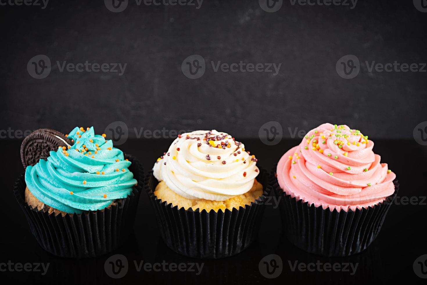 Tasty colorful cupcakes isolated on dark background. Delicious cupcake photo