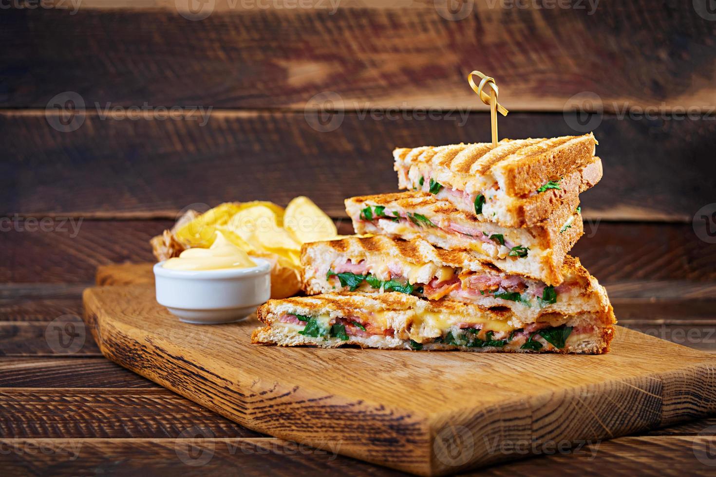 Club sandwich with ham, cheese, tomato, salad and chips photo