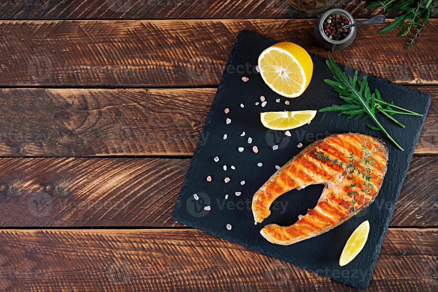 Grilled salmon fish on stone board. Salt atlantic salmon fried on grill with lemon. Top view photo