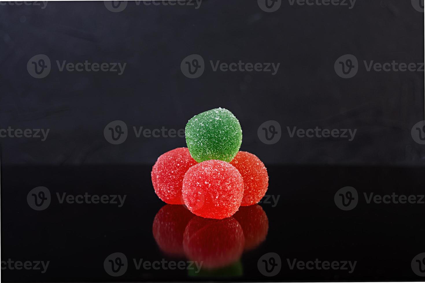 Colorful marmalade isolated on dark background. Delicious jujube balls. photo