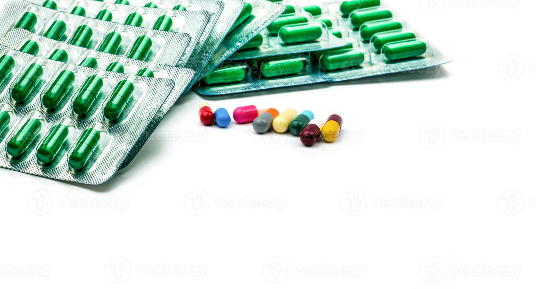 píldora de cápsula antibiótica verde en blíster y píldora de cápsula multicolor sobre fondo blanco. resistencia a los antibióticos y el concepto de medicamentos recetados. productos de farmacia industria farmacéutica. foto