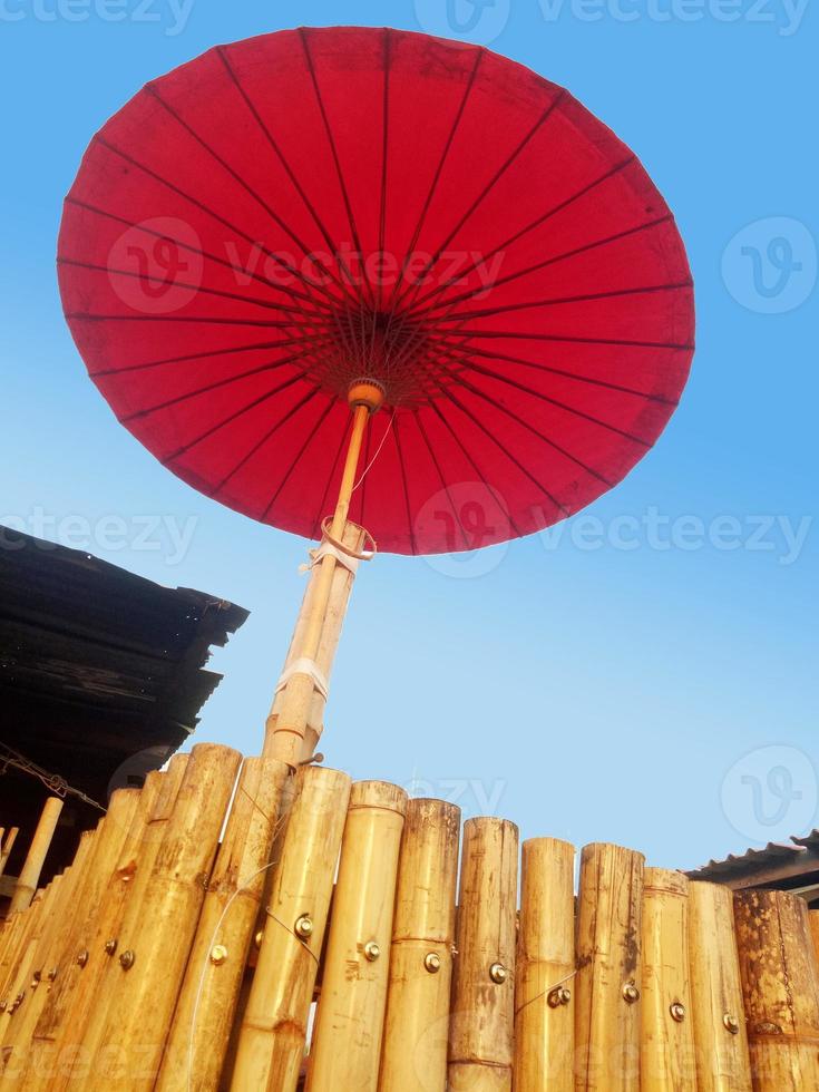 The red umbrella is located on a bamboo trunk. photo
