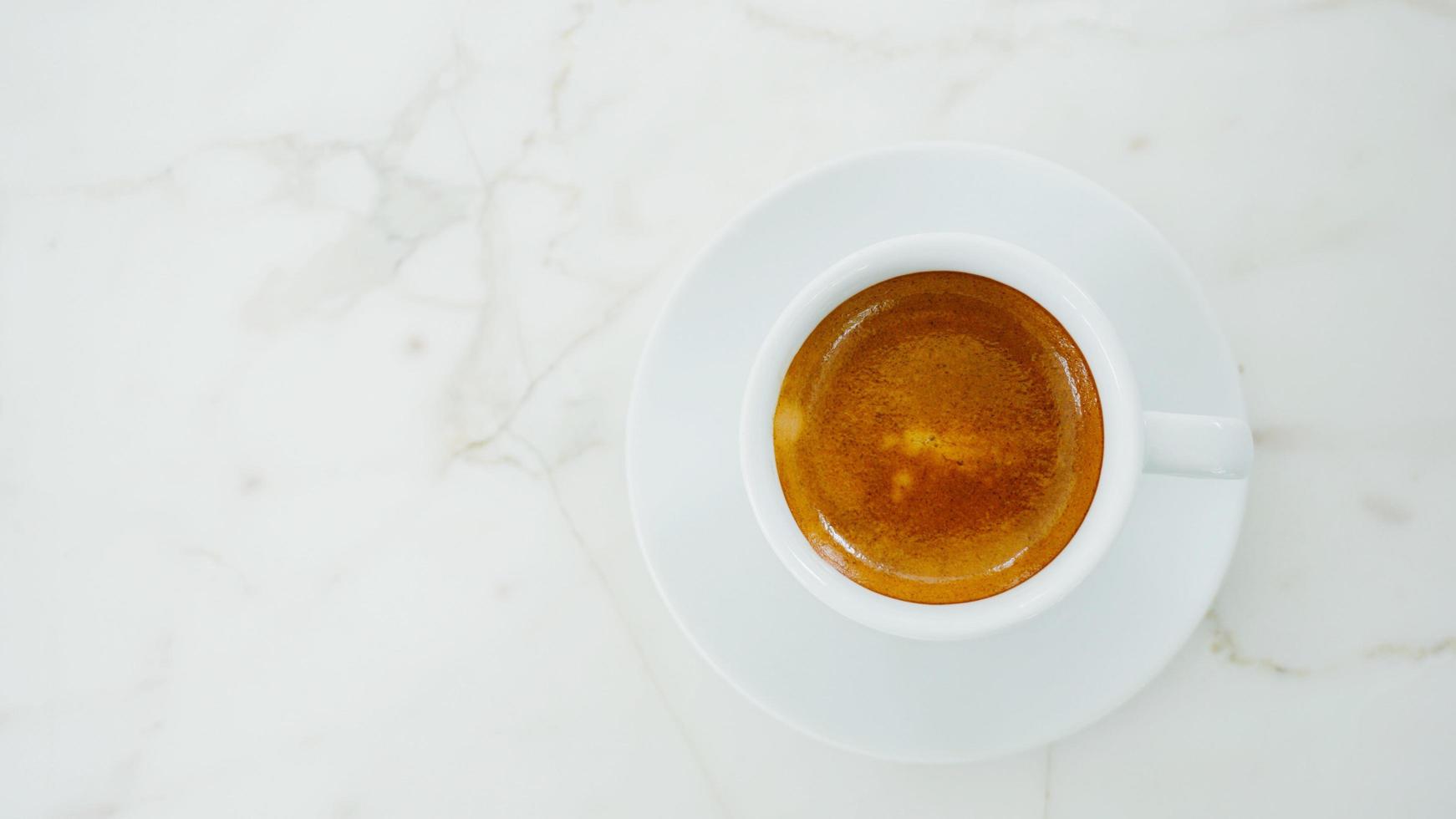 Top view of hot espresso coffee in white mug on white marbel table photo