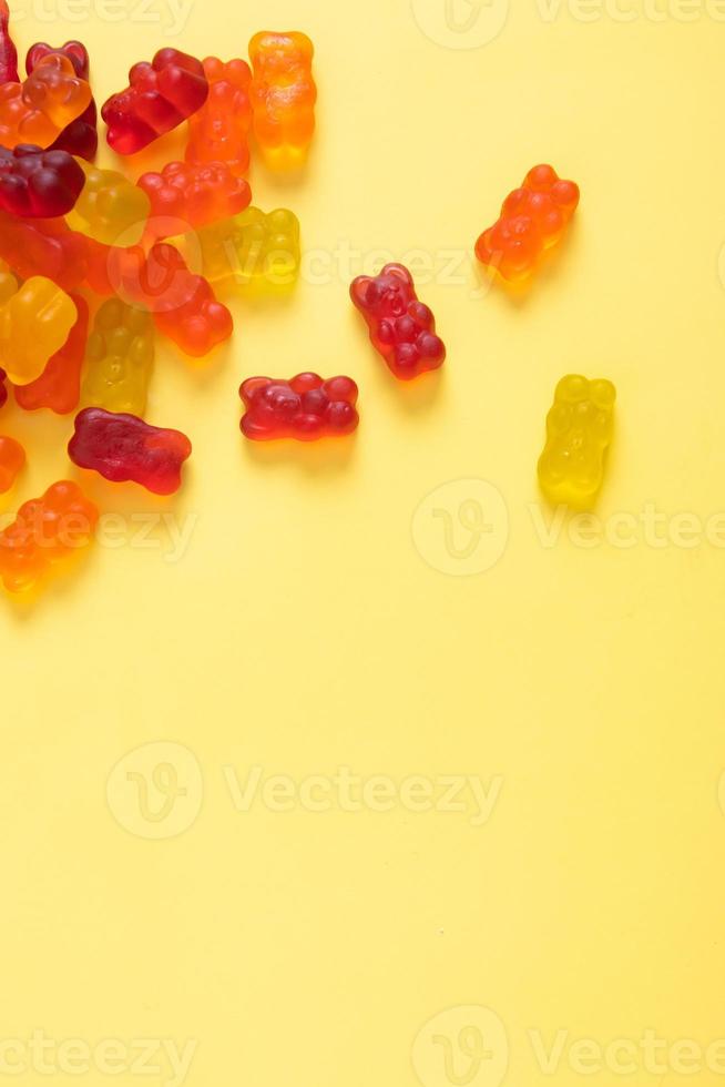 Colored jelly bears on an yellow background with copy space. Top view photo