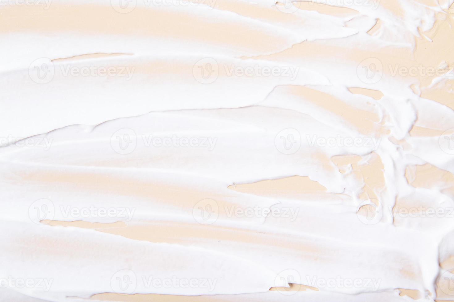 White cream brush strokes top view on beige background photo