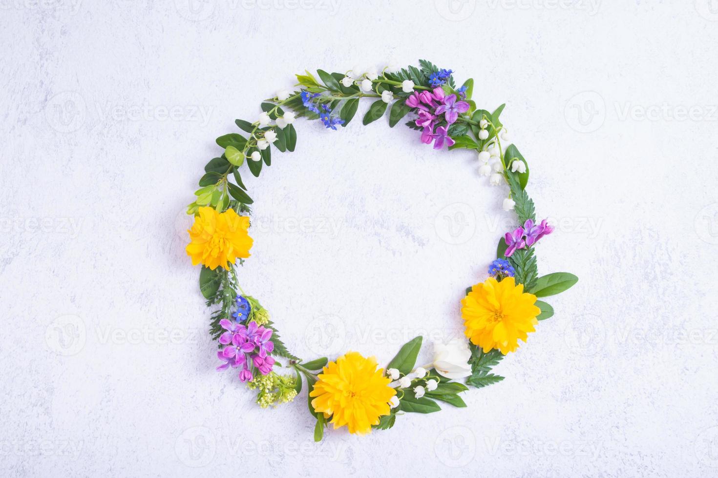 Summer or spring composition on grey background. Purple and yellow flowers, and green leaves with copy space wreath top view. Summer, spring floral concept photo