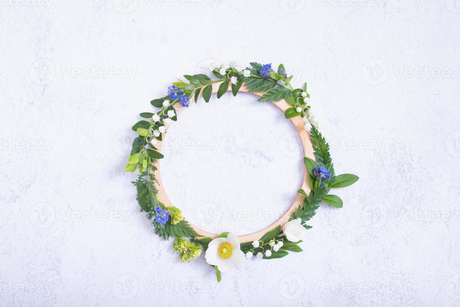 Summer or spring composition on a gray background. Flowers and leaves with round wooden frame copy space top view. Summer, spring floral concept photo