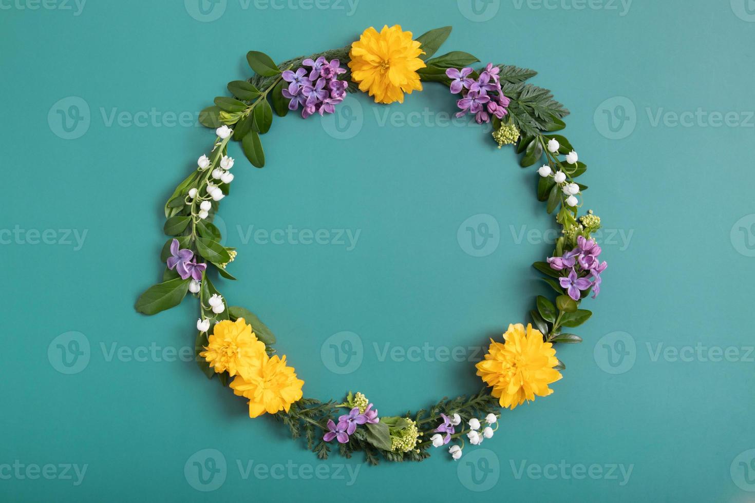 Summer or spring composition on green background. Purple and yellow flowers, and green leaves with copy space wreath top view. Summer, spring floral concept photo