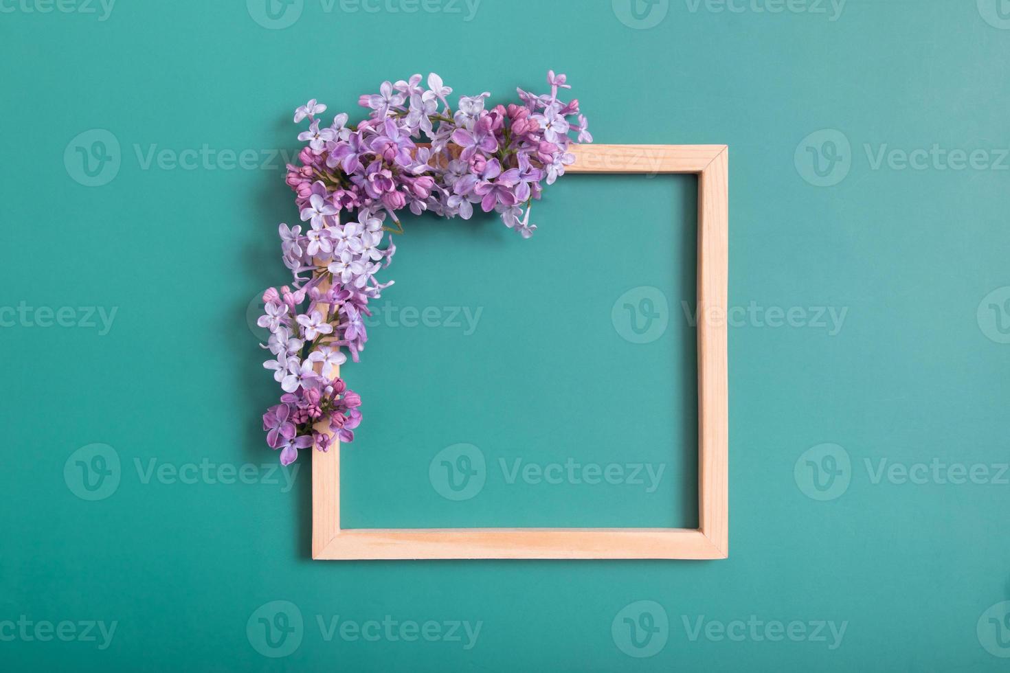 Summer or spring composition on a green background. Lilac flowers with wooden square with copy space top view. Summer, spring floral concept. photo