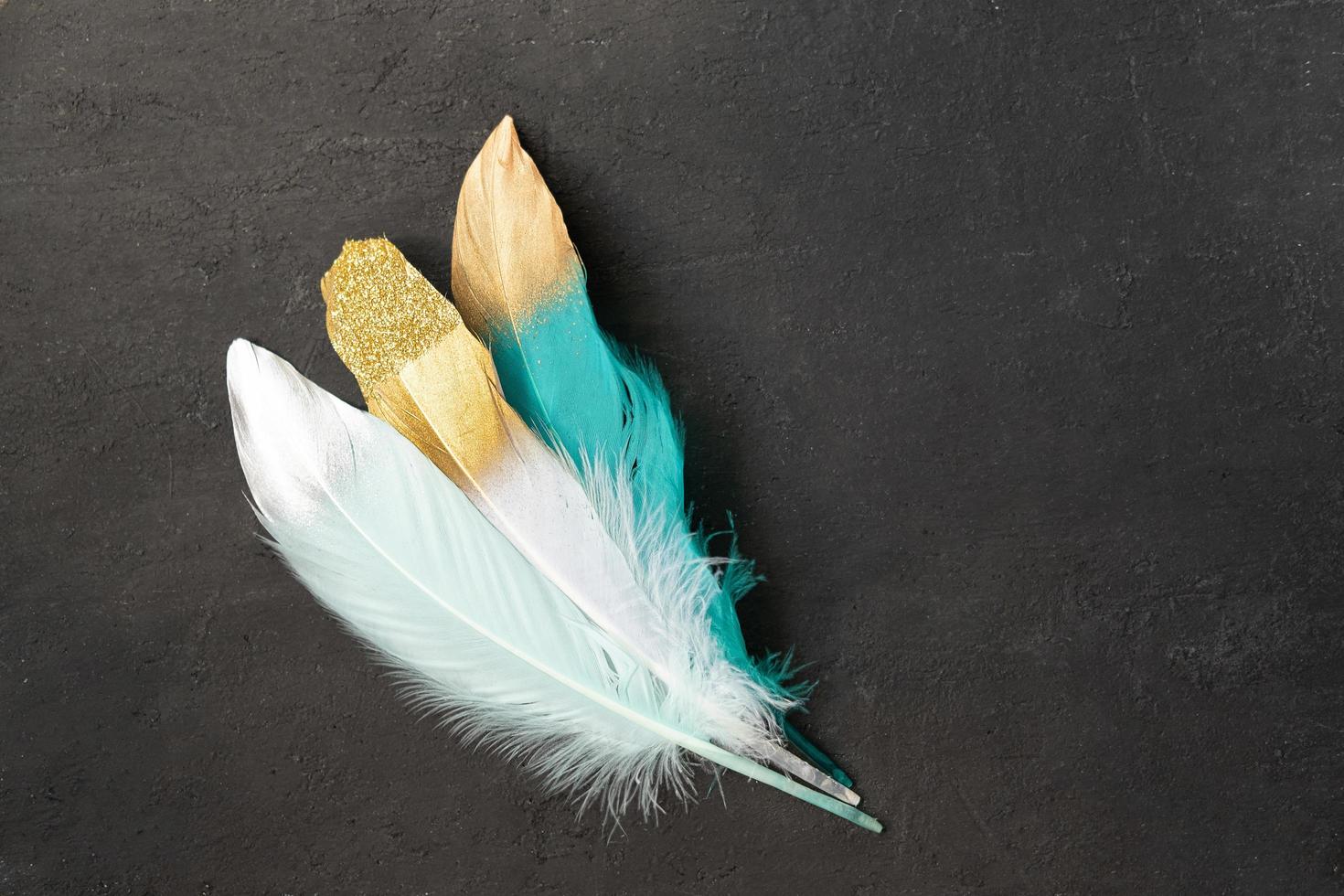 Colored feathers with gold decor on a dark vintage textured background photo