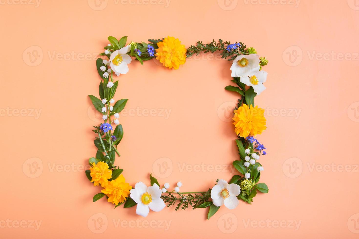 Summer or spring composition on a orangr background. Square frame from flowers and leaves with a copy space top view. Summer, spring floral concept photo