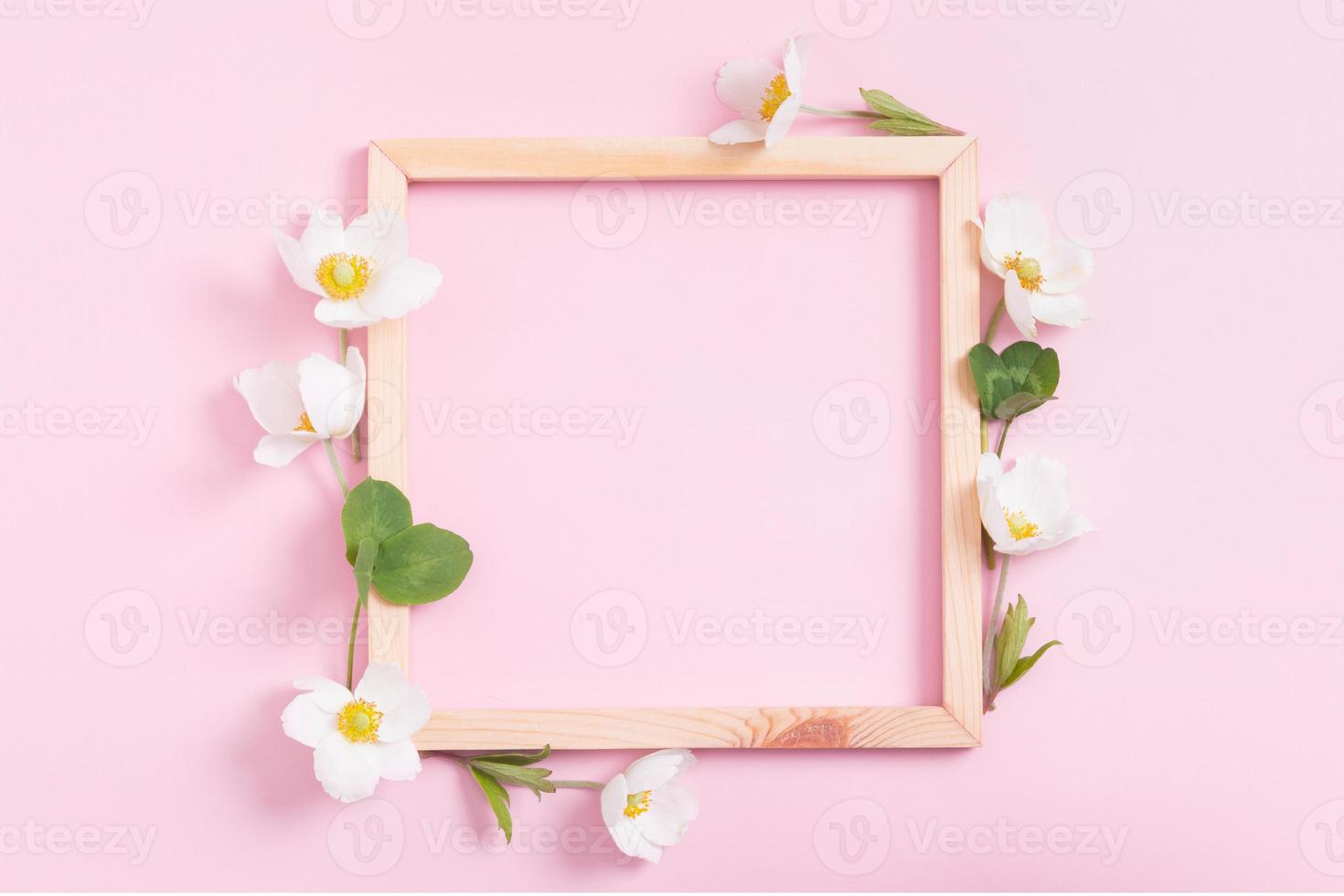 composición de verano o primavera sobre un fondo rosa. marco de madera con flores de anémona con espacio de copia. verano, concepto floral de primavera foto