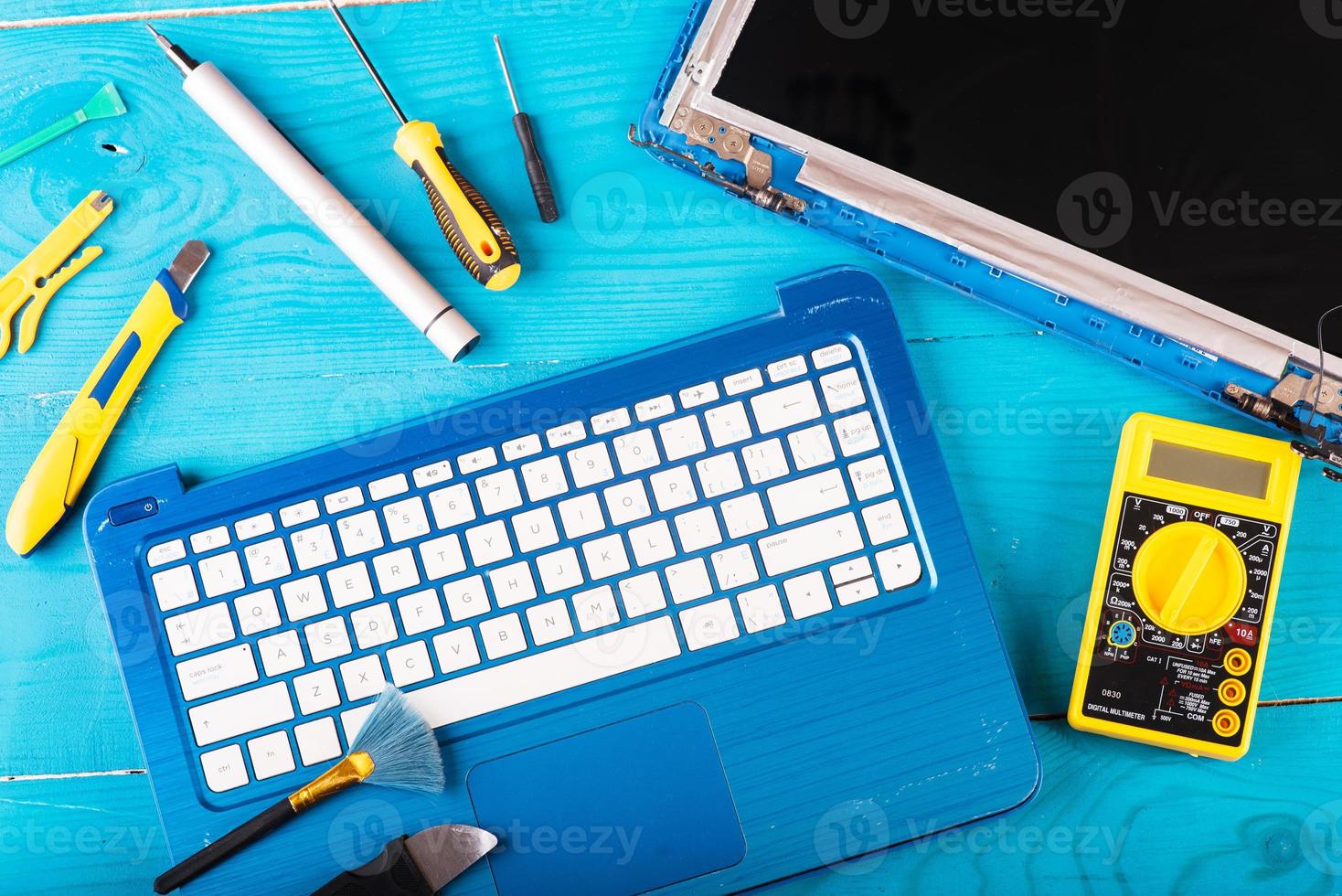 Wizard repairs laptop with tools and hands on the blue wooding table. top view photo