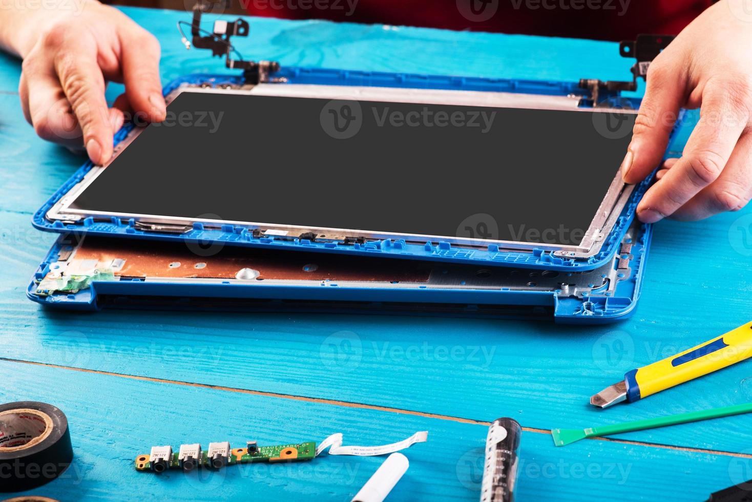 Wizard repairs laptop with tools and hands on the blue wooding table. top view photo