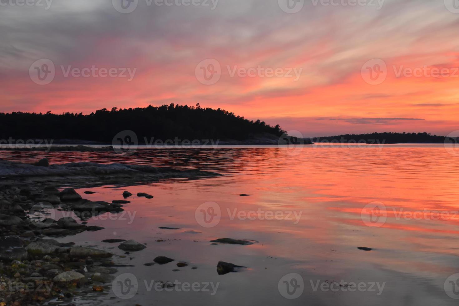 puesta de sol romántica roja sobre un lago en suecia foto