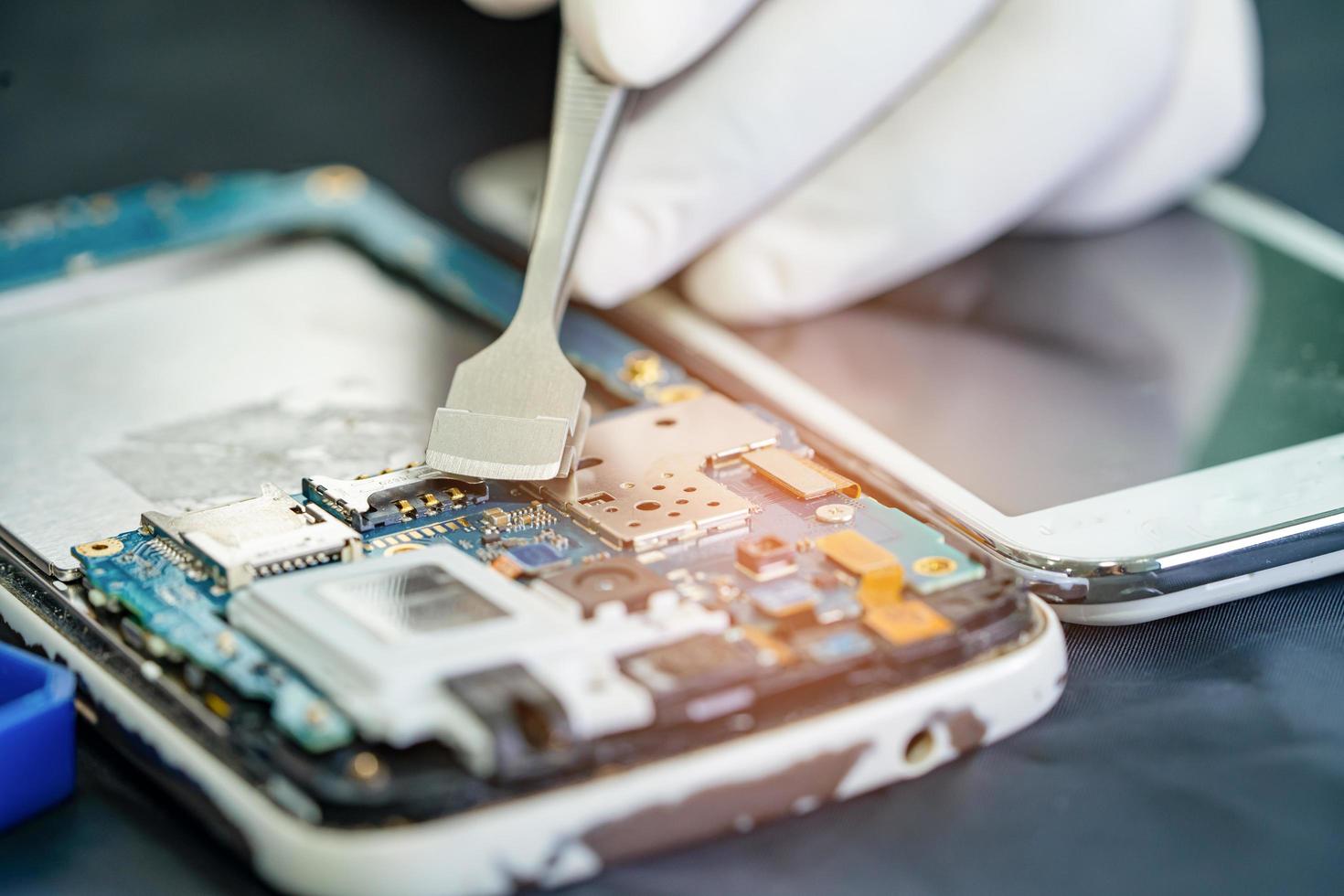 Technician repairing inside of smartphone, Integrated Circuit. the concept of data, hardware, technology. photo