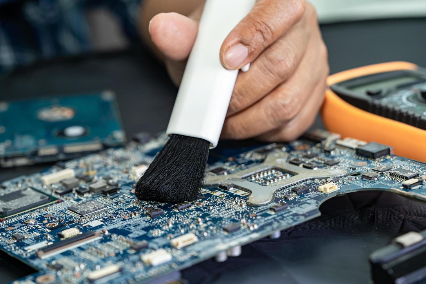 Technician use brush and air blower ball to clean dust in circuit board computer. Repair upgrade and maintenance technology. photo