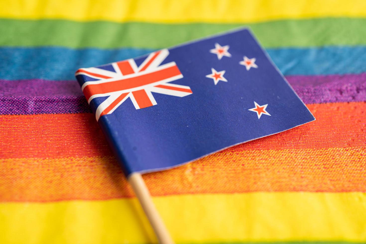 New Zealand flag on rainbow background symbol of LGBT gay pride month  social movement rainbow flag is a symbol of lesbian, gay, bisexual, transgender, human rights, tolerance and peace. photo